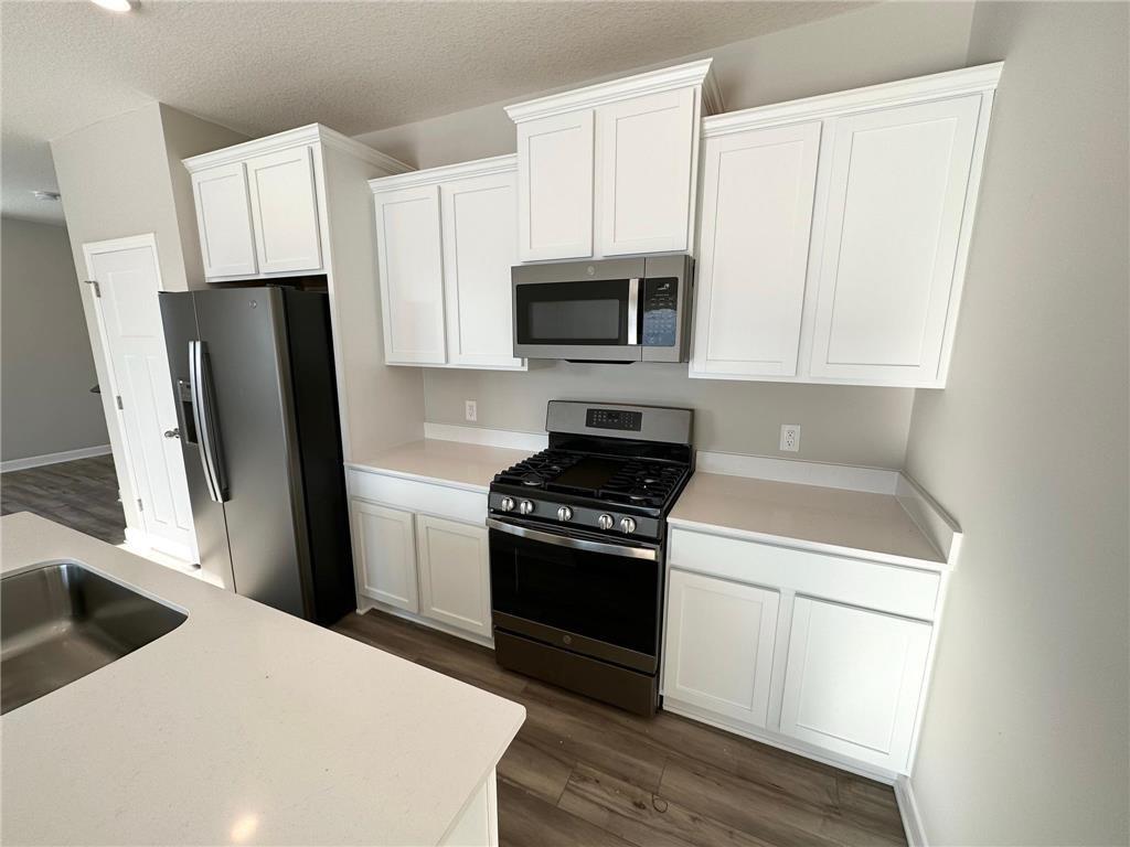 The kitchen features vented microwave, quartz countertops, and slate kitchen appliances. Photo of previously completed home, actual finishes and colors will vary.