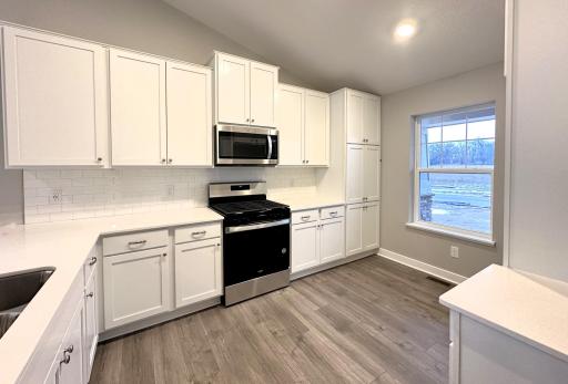 This Rushmore boasts quartz countertops, subway tile backsplash, white cabinets, gray walls and laminate plank flooring throughout the main level. *Picture is of actual home.