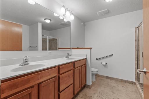 The master bathroom boasts a dual-sink vanity, tile flooring and shower surround, and a separate soaking tub.