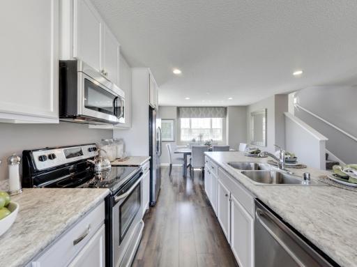 Microwave is vented to outside and matches other stainless steel appliances. Photos from previous model home, finishes and options to vary. (Photos of the same floorplan, colors are similar).