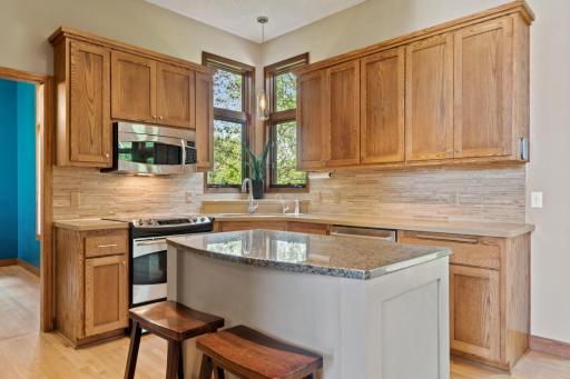 Kitchen with granite, tiled backsplash, SS appliances.