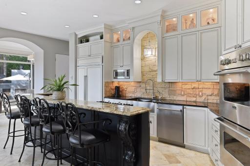 Masterfully crafted with detailed corbels, the extensive custom cabinetry is outfitted with pull-out shelving, a recycling center, and seeded glass cabinet doors lit with accent lighting.