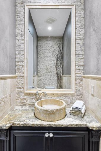 Totally refreshed, the powder room on the main level features stone and tile accents with a granite topped vanity and a new toilet.