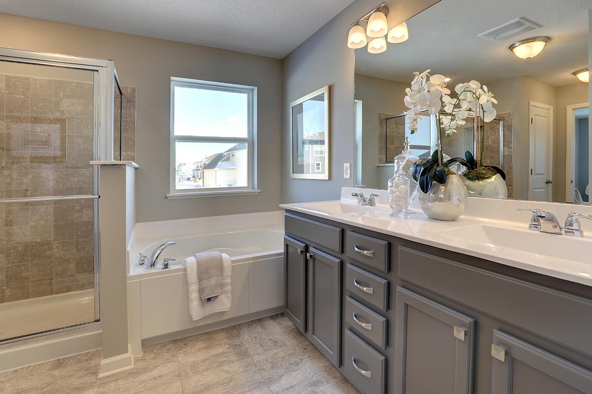 An extension of the primary suite, this private and spacious bathroom contains a double-vanity, a separate shower and tub and a private water closet. Photo of model, colors and options will vary.