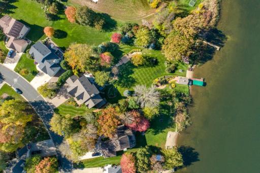 Aerial view of home with lush landscaped backyard with boathouse, firepit, waterfall, pond, pergola, flagpole, gardens and more! BEST LOT on the lake.