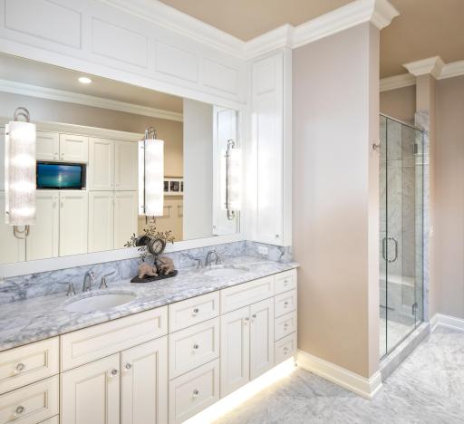 Owner's ensuite bath with double vanity areas, large walk-in shower, and plenty of cabinet space for linens and other personal items