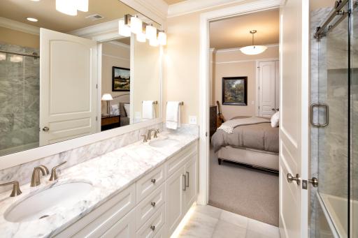 Ensuite full bath features dual vanities, tub/shower combo, and linen cabinets