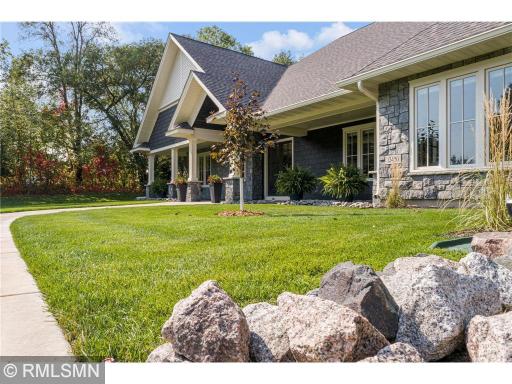Granite boulders in the landscape beds and granite stone work adorn the exterior of the home and pillars.