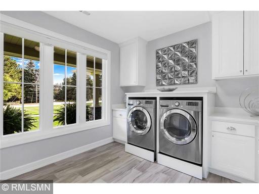 A laundry room with wonderful working spaces highlighted with snow white quartz countertops and ceramic plank-style flooring.