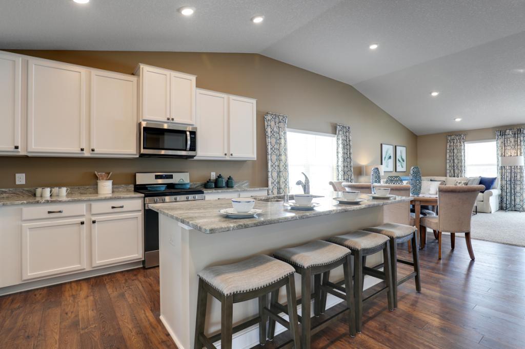 A stunning kitchen layout, all while remaining remarkably functional: Granite countertops, under-mounted sink, gas cooktop, vented micro-hood - all soaked in natural light! Photo of model, colors will vary