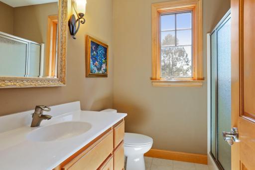 Just off the mud room is a 3/4 guest bathroom with an elevated vanity, designer mirror and tiled flooring.