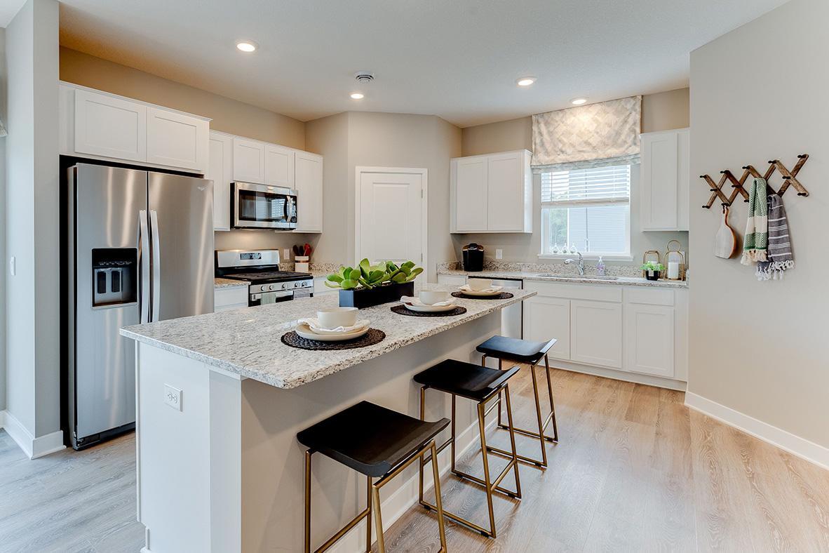 Open and spacious kitchen with stainless steel appliances, kitchen window, and granite countertops. Model home photo, actual home will vary in finishes.