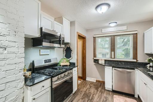 Functional & updated kitchen with newer SS appliances, vinyl plank flooring, and granite counters