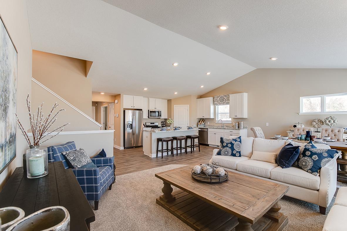 Main level living room and a glimpse of the entryway, guests arrive and flow right into the main floor. Model home photo, colors and selections may vary.