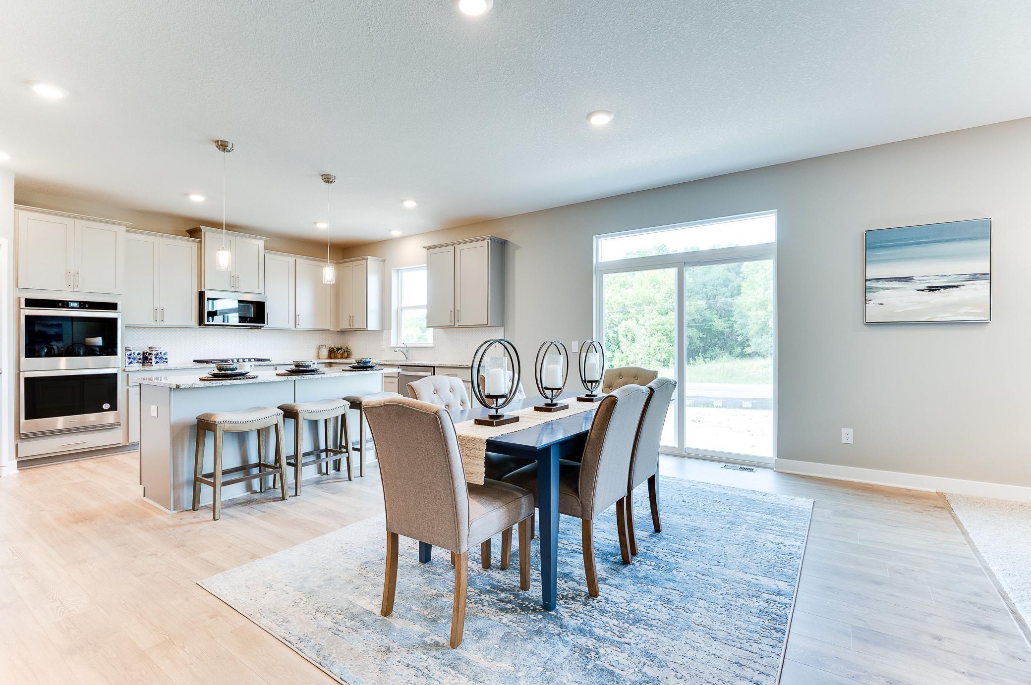 Centered within the main level, the home's dining space spans nearly 17-feet wide and rests just adjacent to the easy access onto your future deck! Photo of model home, color and options will vary.