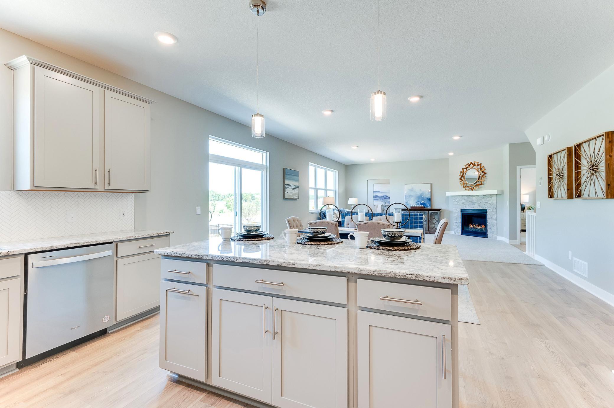 The rest of the main level pours out from the home's kitchen, as the layout flows seamlessly from the kitchen space into the dining and living areas! Photo of model home, color and options will vary.