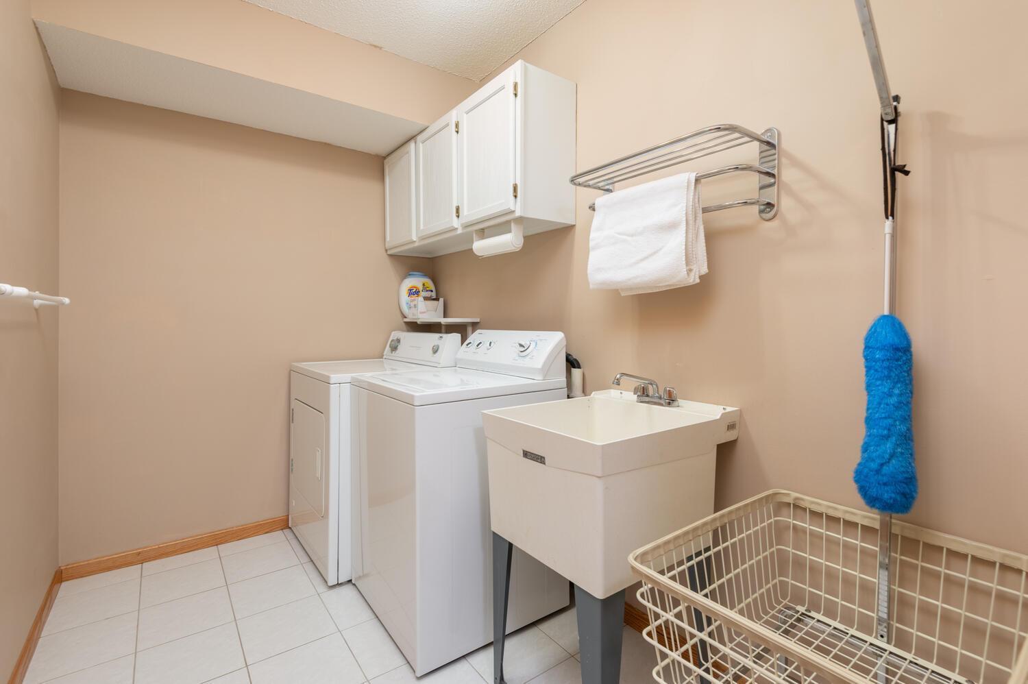 Finished lower level laundry room with ceramic tile flooring, laundry tub and storage cabinet. Very nice and clean!