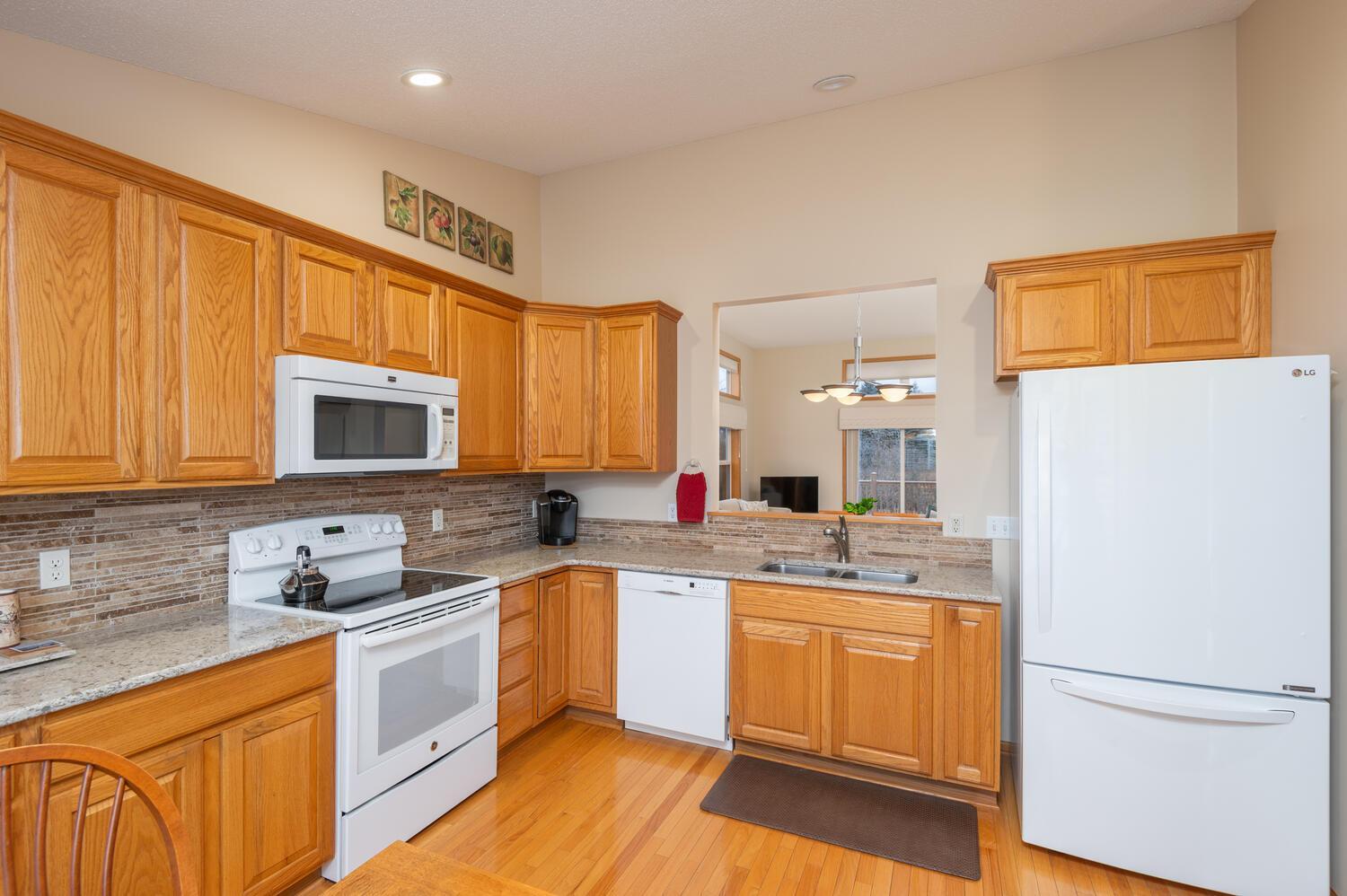 Eat-in kitchen includes newer granite counters and sink with a stone backsplash, updated appliances and pull out shelves for convenience.