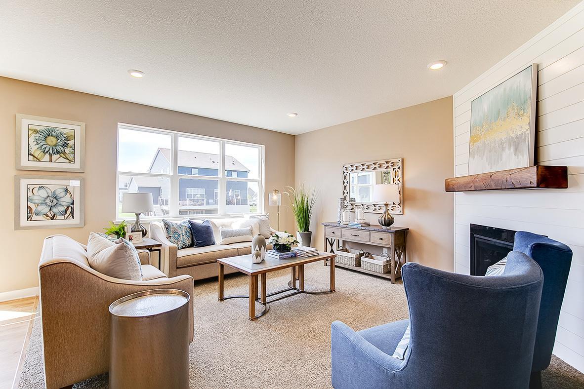 Soaring windows flood your main level family room in natural light - a space punctuated by a glowing corner gas fireplace. Photo of model home, color and options will vary.