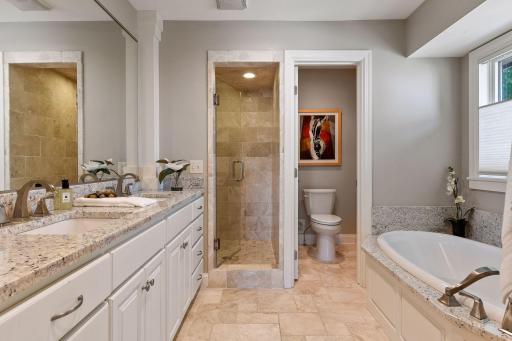 Classic tile and granite create a spa feel in the primary bathroom.