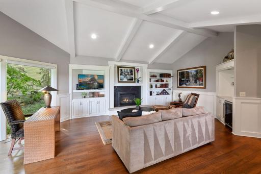 The main floor family room is well-appointed with built-in shelving, mini-frig, a beam ceiling and beautiful wood floors.