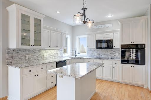 Kitchen features enameled cabinetry, granite counters & stone backsplash