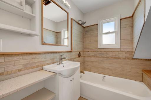 The upper full bath was completely renovated, with beautiful stone tile. The radiator here would make a great towel/robe warmer in the winter!