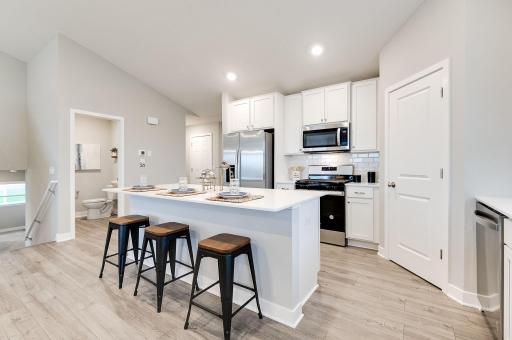 A true designer kitchen; Quartz countertops complimented by tile backsplash, a massive island, plenty of cabinet space, plus a walk-in pantry! Photo of model, colors and options will vary.