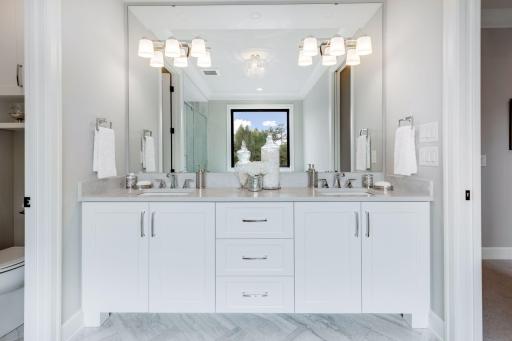 The private Master Bathroom features a comfort height vanity with two sinks, tiled flooring and designer fixtures. Photos of similar model.