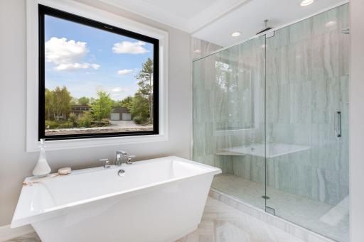 The bathroom also offers a large free-standing tub and separate tiled shower. Photos of a similar model.