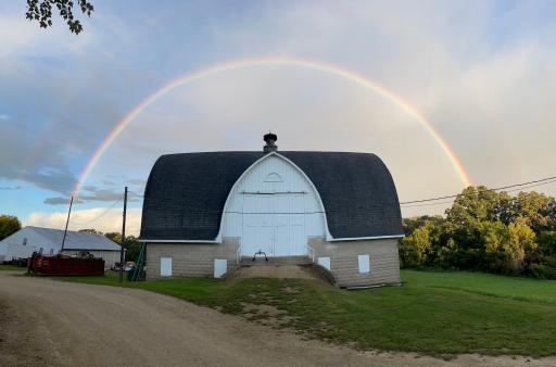Unique barn with gable entrance on the upper level. The beauty of a rainbow after a storm perfectly frames the barn. The lower level could be for horses or goats or cows or...