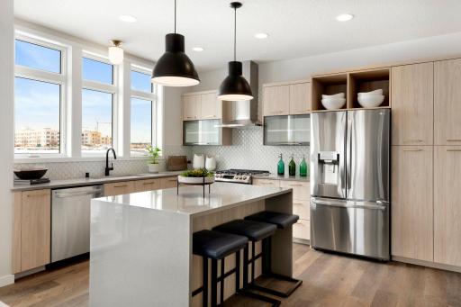 Modern kitchen features quartz countertops, waterfall island, stainless appliances and custom tile backsplash.