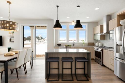 Modern kitchen features custom cabinetry, large windows and waterfall island.