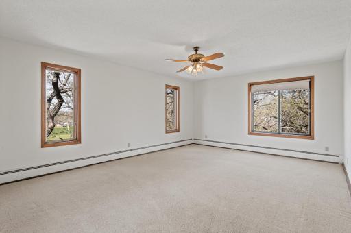 Enormous primary bedroom oasis providing views of the golf course, and wooded backyard.