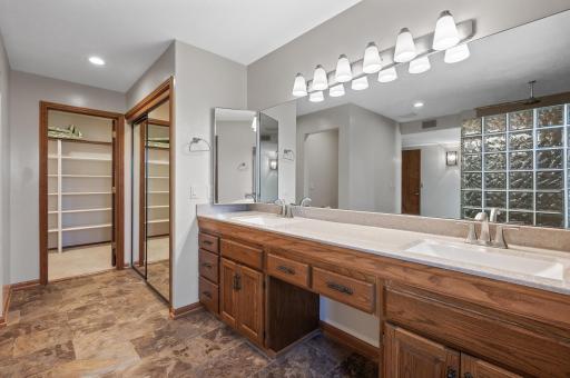 Luxurious private bathroom with dual sinks, spa like walk-in shower, and large walk-in closet with built-ins.