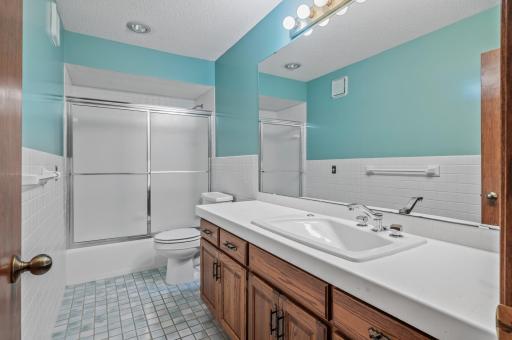 Full shared bathroom with shower/tub combo, large vanity & tile surround.