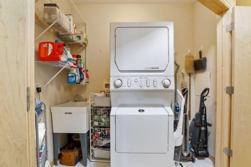 What convenience! The laundry room is complete with a stacking washer and dryer, plus a utility sink and storage.