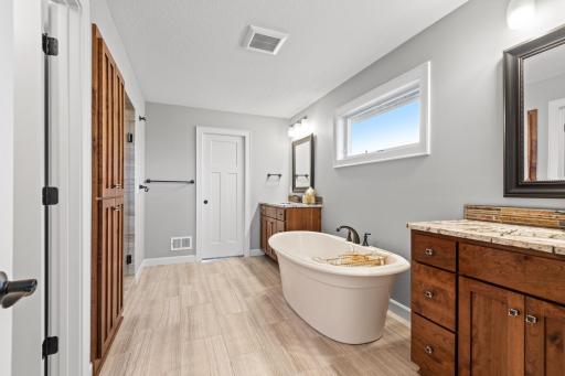 The spa-inspired master bath features his and hers vanities with granite countertops, free-standing soaking tub, compartmentalized toilet, large walk-in shower and built-in cabinets.