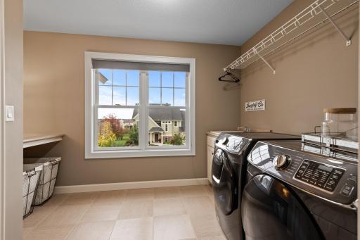 The large laundry room is conveniently located on the upper level. It features tile floors, Samsung front-load washer & dryer, laundry sink with built-in cabinets, folding counter, shelving & plenty of room for hanging.