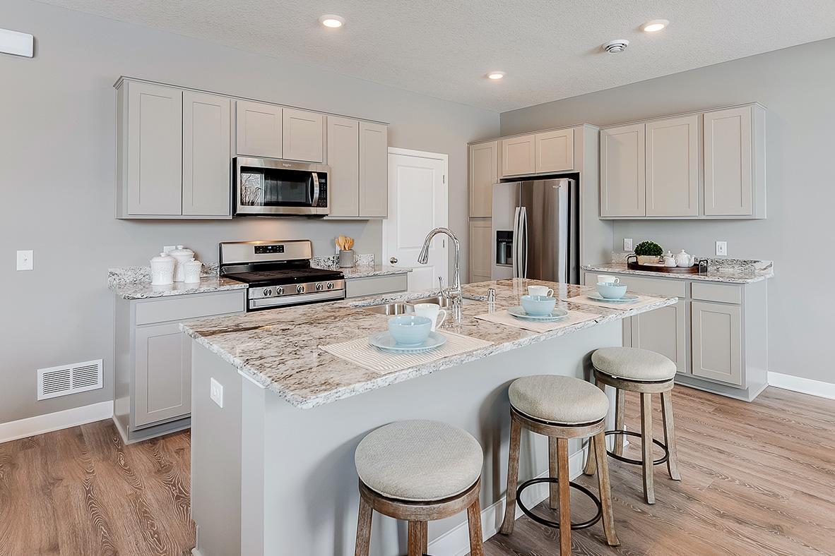 A kitchen built to perform! Stainless appliances including a vented microwave, gas range and dishwasher. Gray cabinets and granite counters. Photos of model. Options and colors may vary.