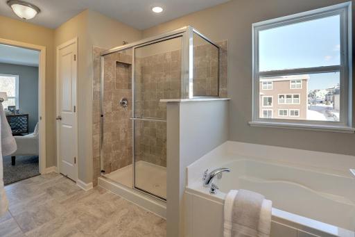 Tile shower in the primary suite. *Photo of previous model. Selections may vary, please see agent for details.