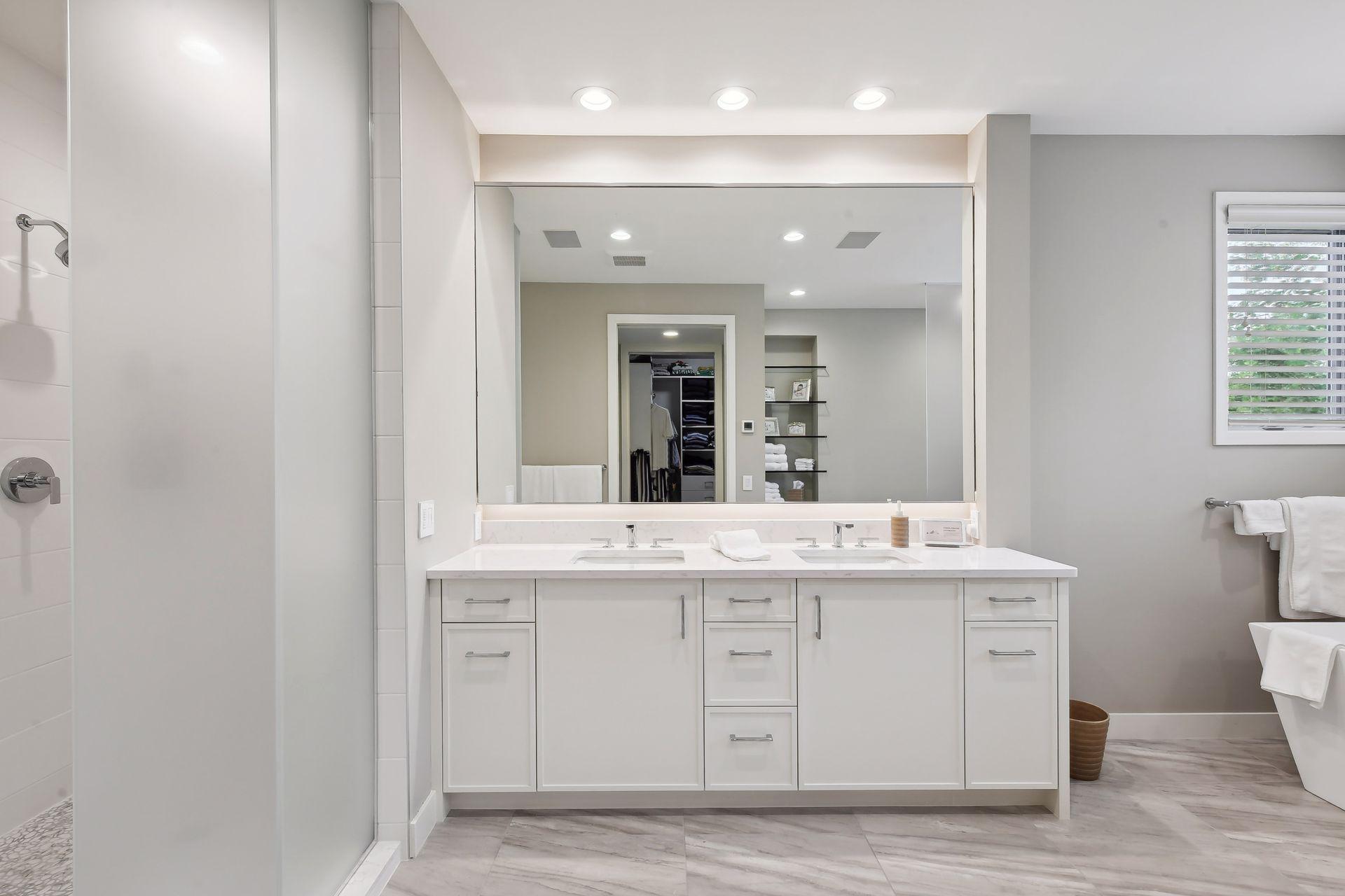 Updated primary bathroom with double sinks across from primary walk-in closet