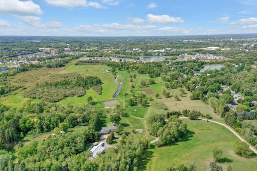 Westerly view, Driveway on the right side of photo and pole building roof and house a little left of bottom center. Land extends back to wetlands on the west and south prior to development areas.