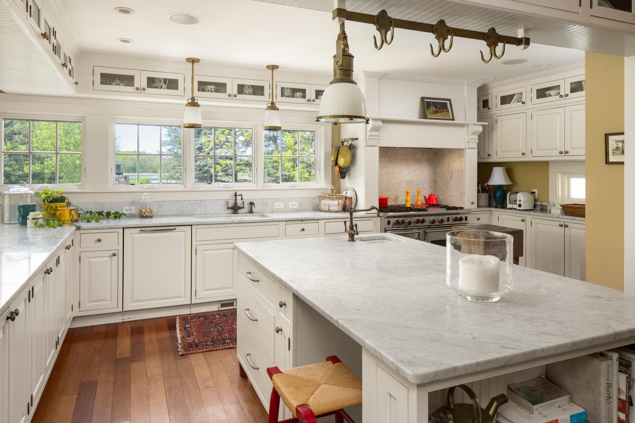 The gourmet kitchen is filled with natura light, a large center island with seating and storage, Viking six burner range with professional exhaust hood, Marble countertops, ample storage, and Sub Zero refrigerator.