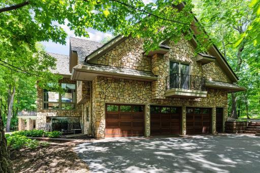 Unique stone exterior with cedar shake roof and wood panel garage doors