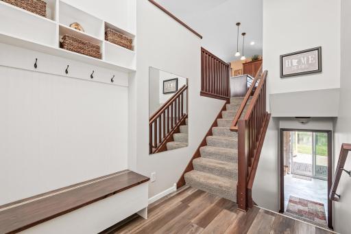 Beautiful foyer with white trim, new LVP floors and built in mitten/hat bench and coat hooks.