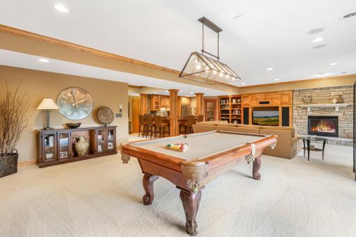 You will find a spacious family room featuring a gas fireplace with stone surround and built-ins, plus an oversized adjoining area perfect for billiards and game tables.