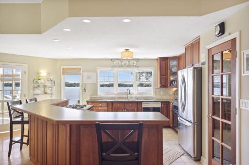 The kitchen offers panoramic lake views along with Cherry cabinetry, neutral backsplash, under mount lighting and a large island with room for guests.