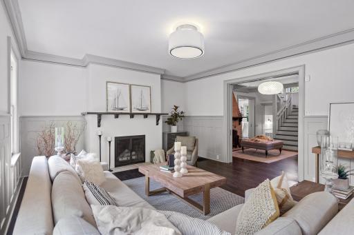 The lovely living room has another wood-burning fireplace, divine millwork including chair rail surround, and a big window where you can see the lake through the porch!