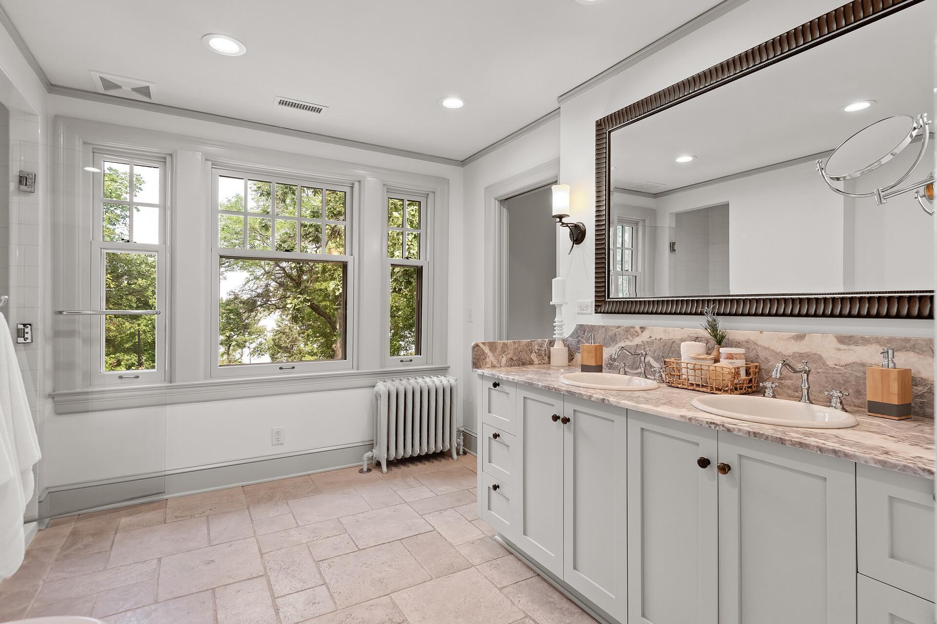 Large bathroom with dual sinks and fully tiled walk-in shower, and even a view of the lake!